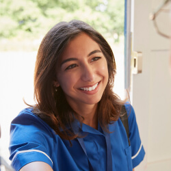 A person in a blue uniform smiles while standing at an open door.